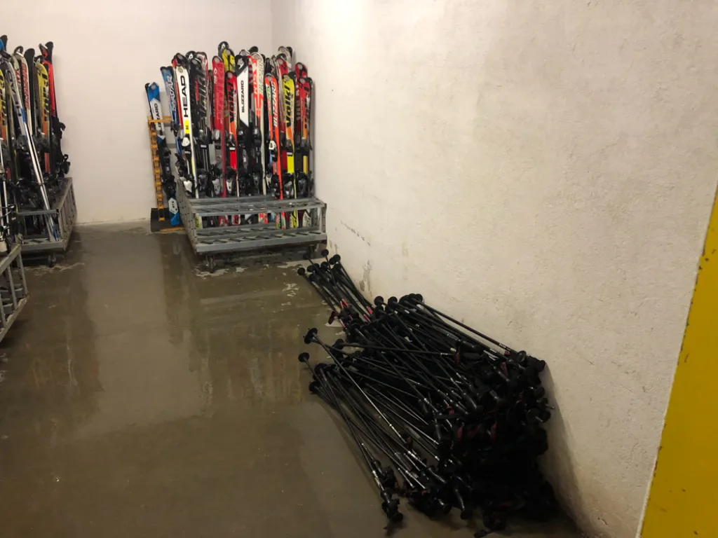 Skidepot mit Ständern voller Ski und Stöcke.